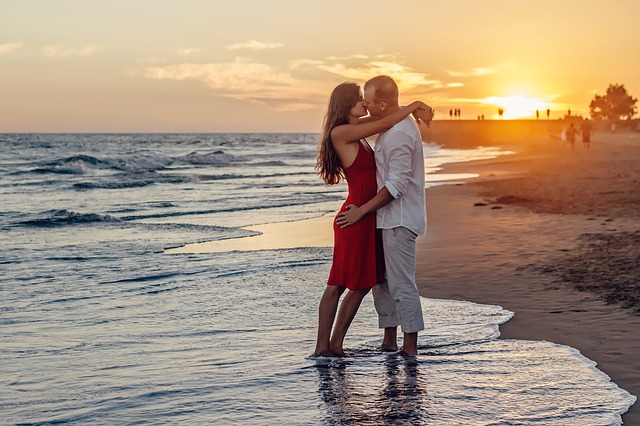 a couple kissing by beach at sunset